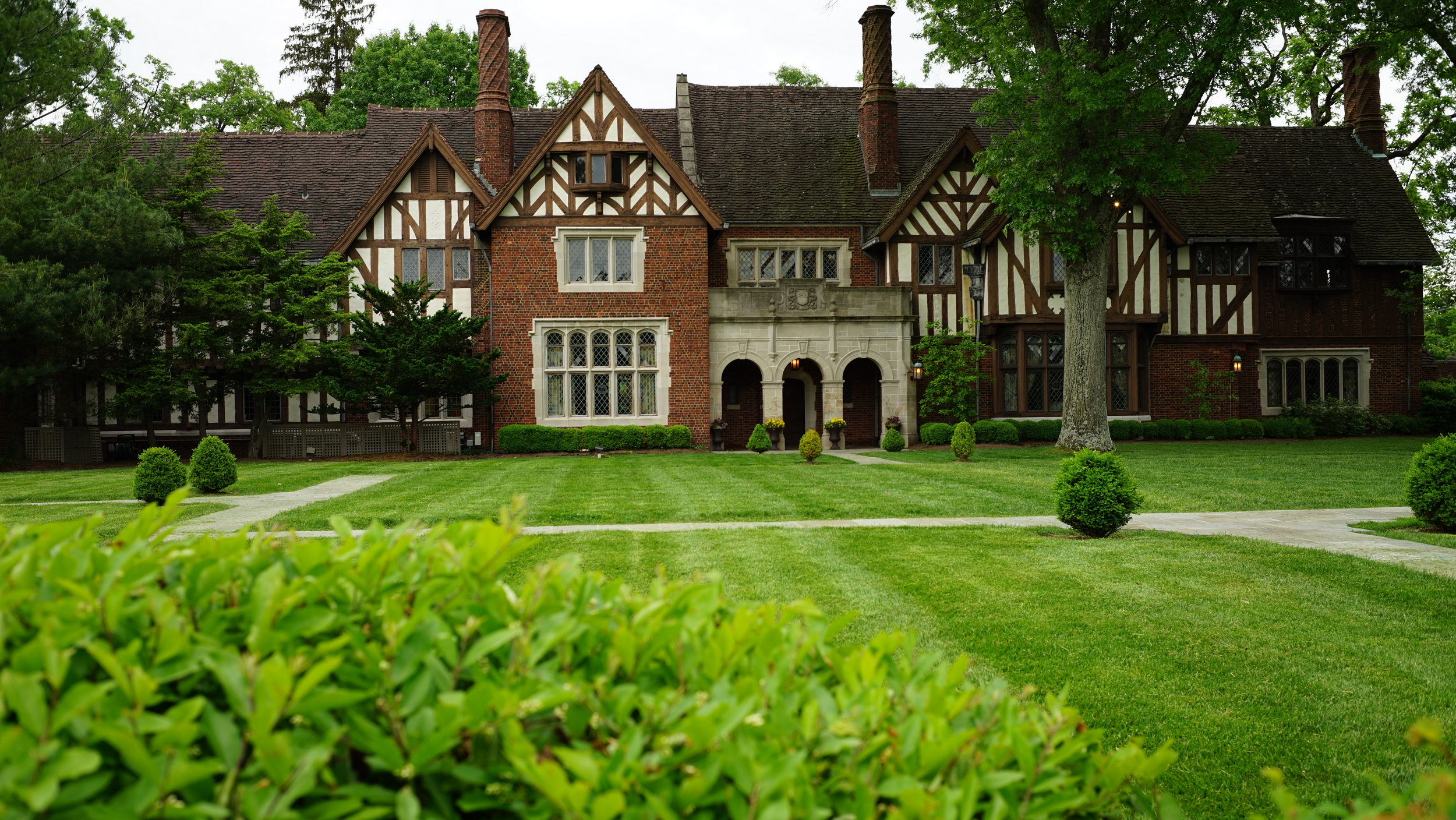 Historic brick mansion with green lawn and trees.