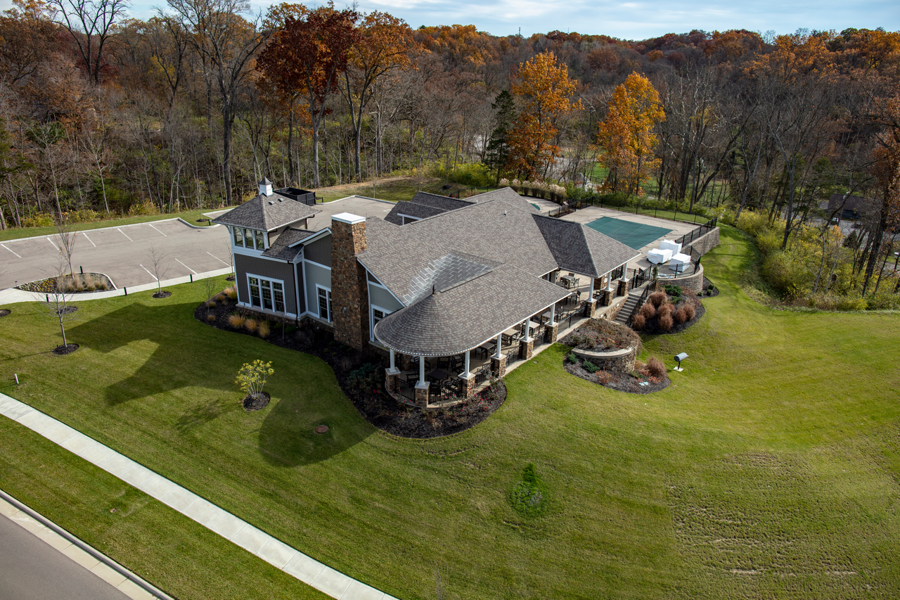 Aerial view of a large house with a pool, surrounded by green lawns and autumn trees.