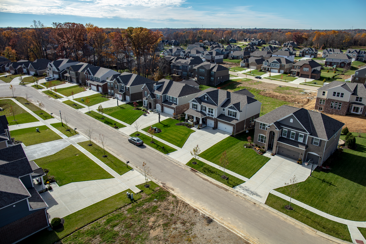 Suburban neighborhood with rows of houses, green lawns, and wide streets.