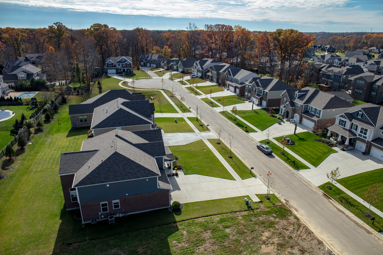 Suburban neighborhood with houses, lawns, and a clear blue sky.