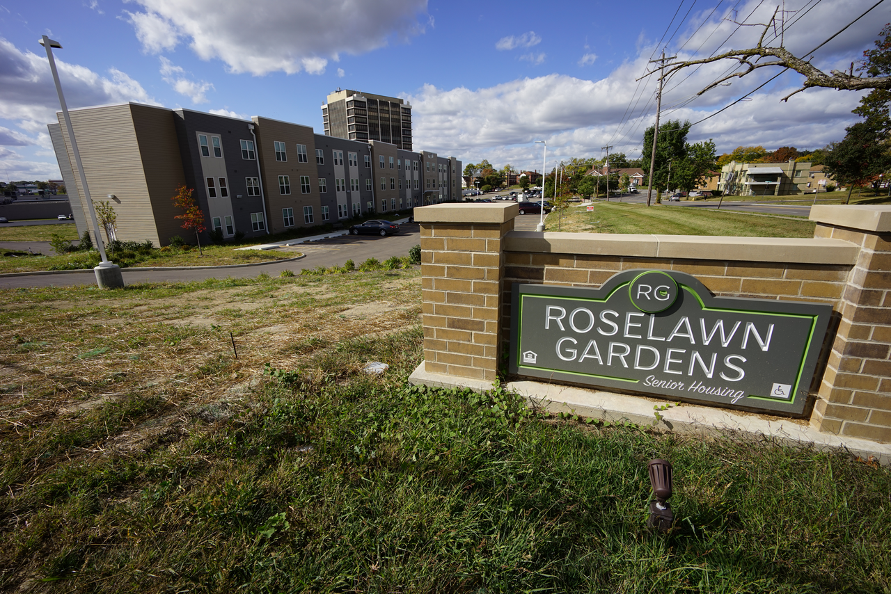 Roselawn Gardens entrance sign with buildings in the background.