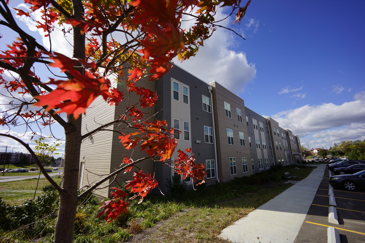 Four-story apartment building with red leaves in foreground.
