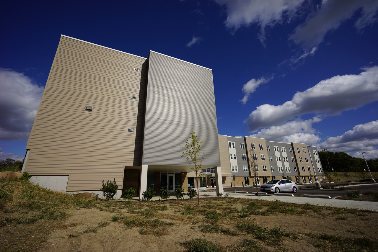 Modern apartment building under a blue sky with scattered clouds.