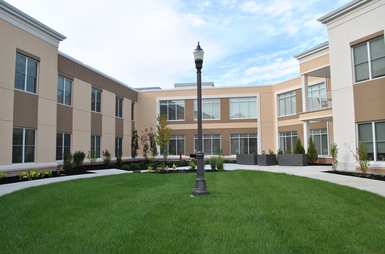 Courtyard with grass, lamp post, and surrounding buildings under a blue sky.
