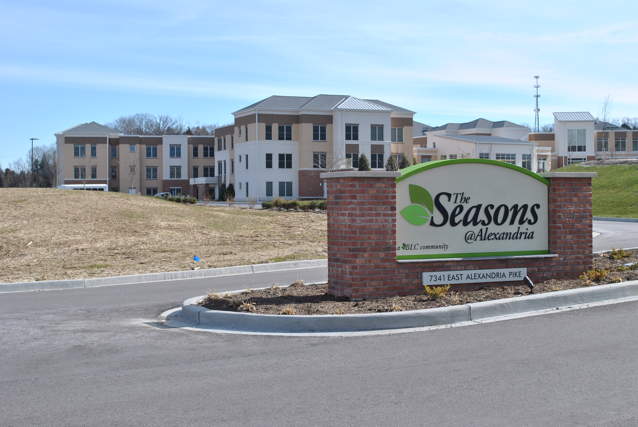 Entrance sign to a residential complex with buildings in the background.