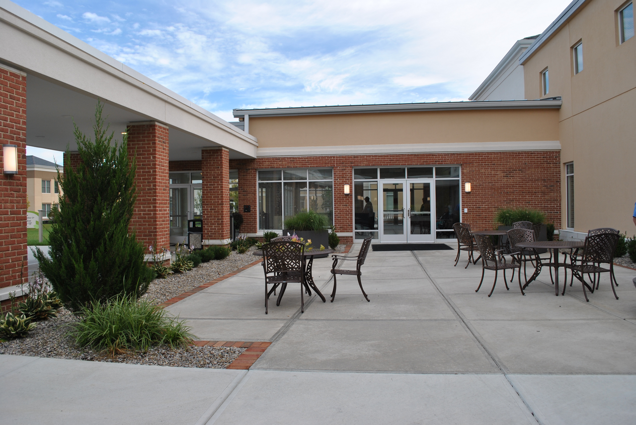 Outdoor patio with tables and chairs, surrounded by a brick building.