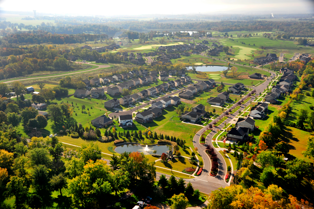 Aerial view of a suburban neighborhood with houses, roads, and greenery.