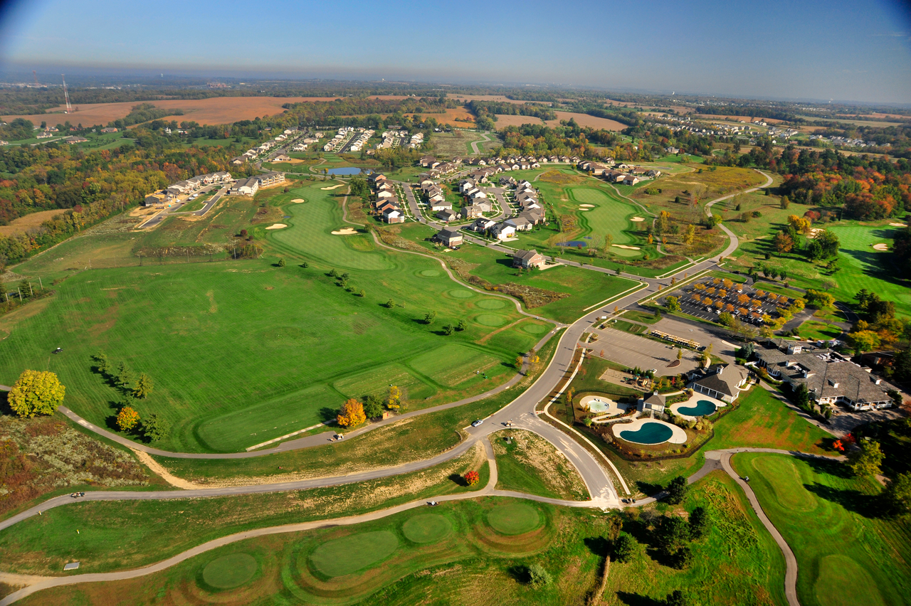 Aerial view of a golf course with surrounding houses and trees.