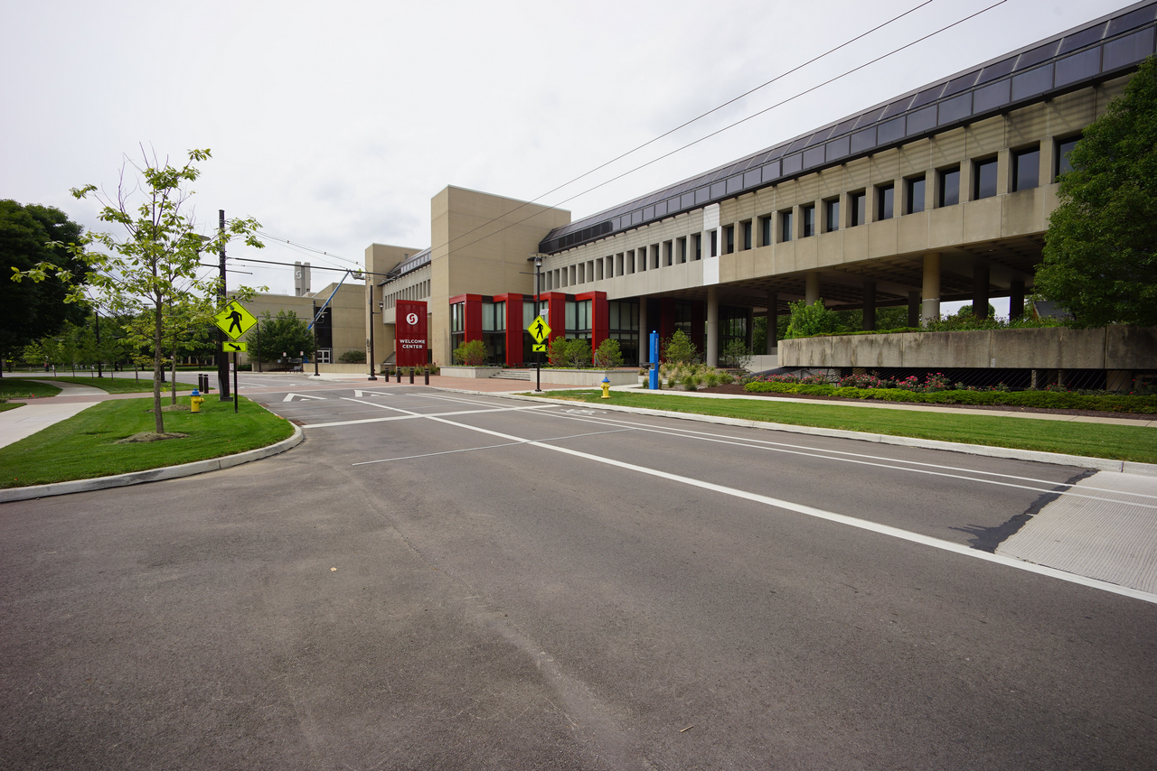Modern campus building with trees and crosswalks on a cloudy day.