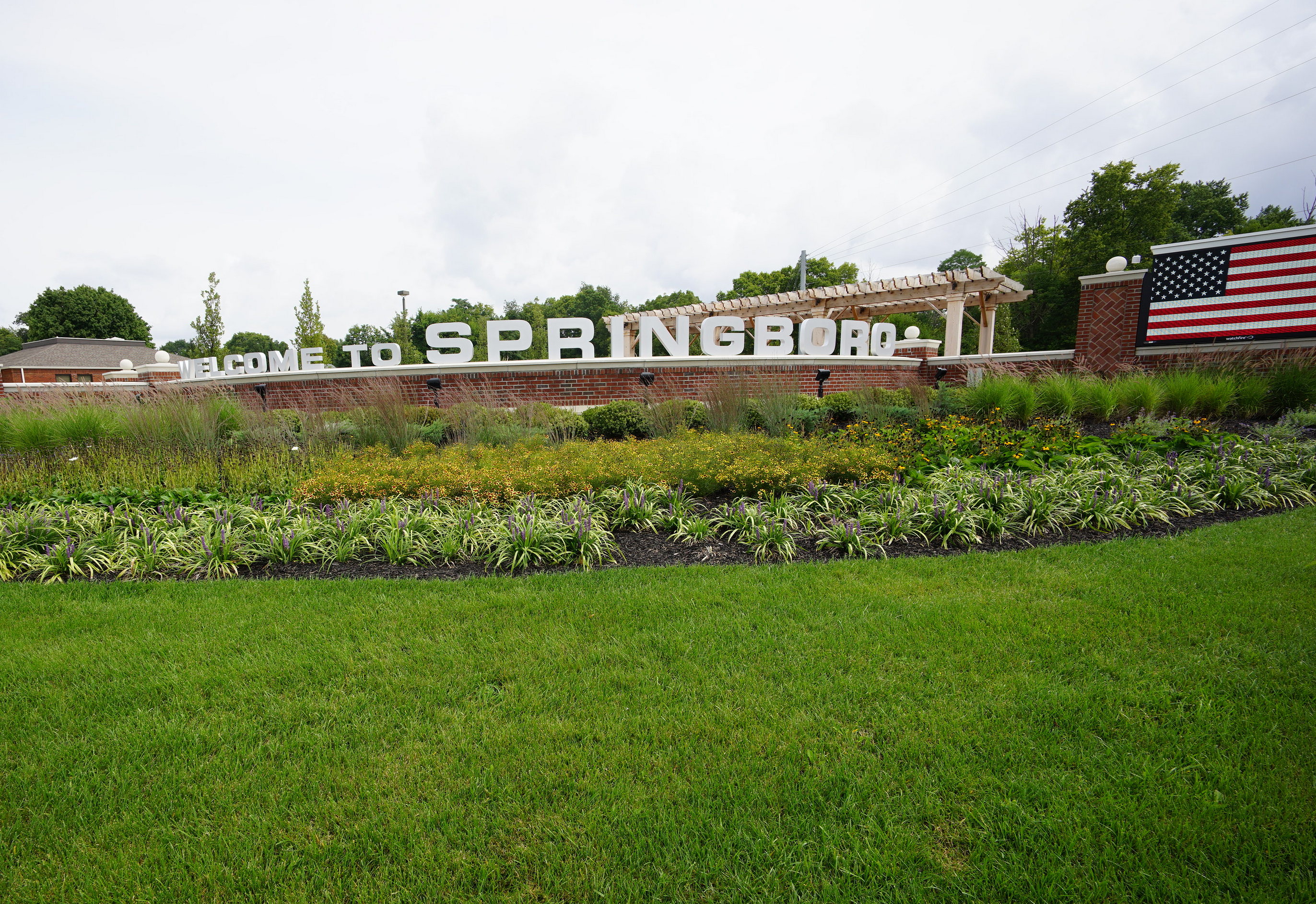 Welcome sign to Springboro with flag and landscaped greenery.