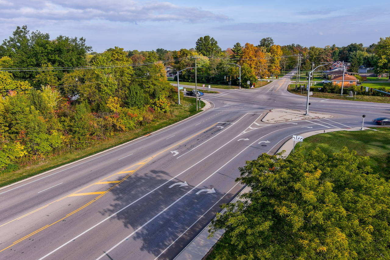 Wide intersection with tree-lined roads, under a clear sky.