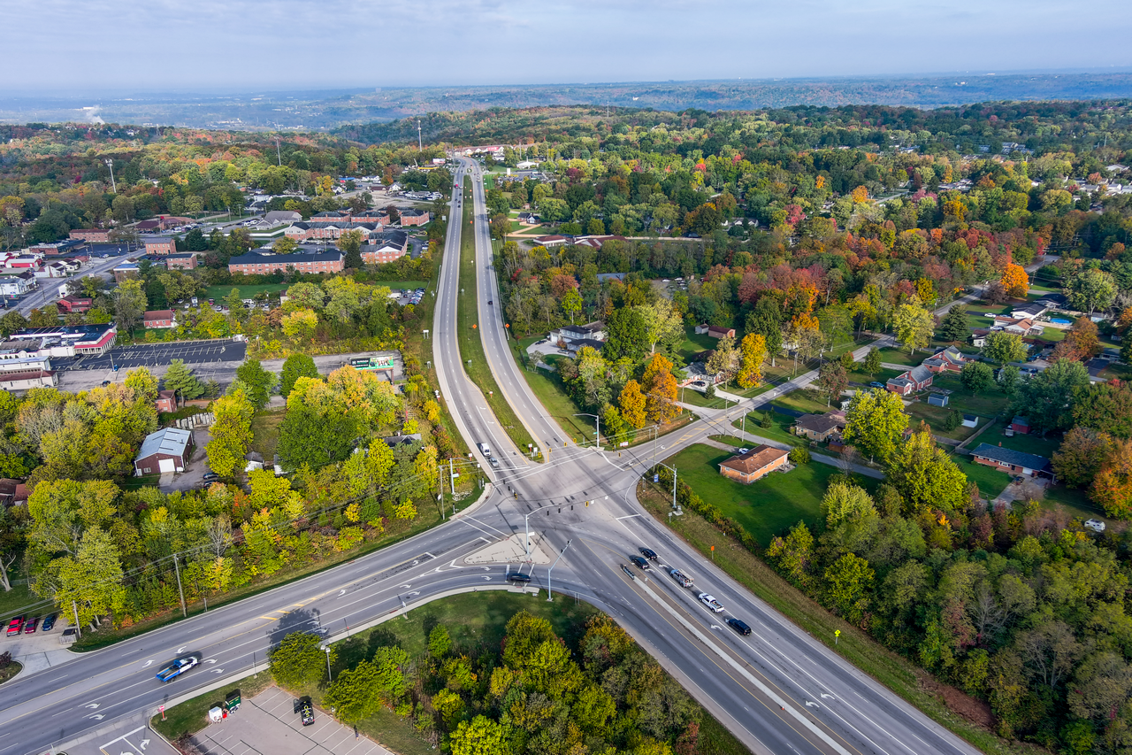 Aerial view of a highway intersection surrounded by trees and houses.