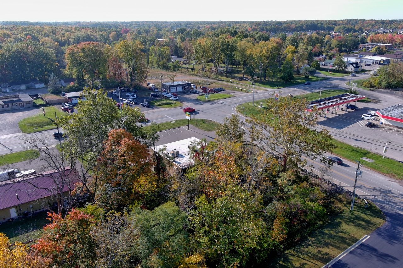 Aerial view of a suburban area with roads, trees, and parked cars.