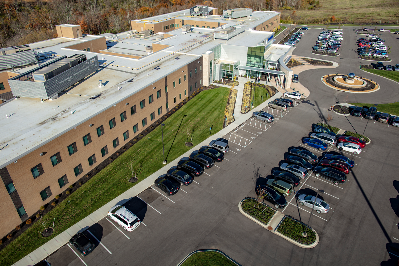 Aerial view of a large building with adjacent parking lot and circular driveway.