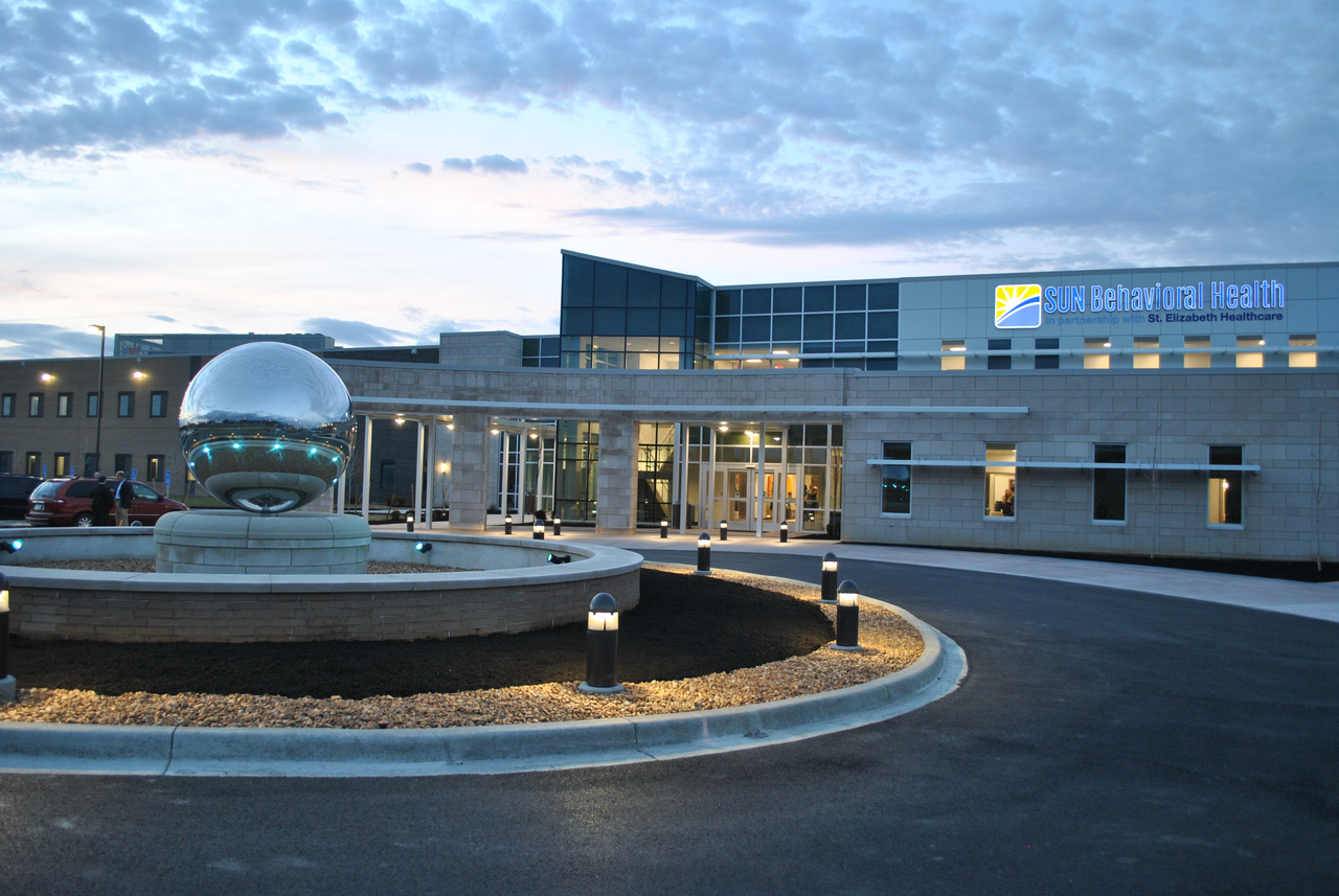 Modern hospital entrance with large glass windows at twilight.