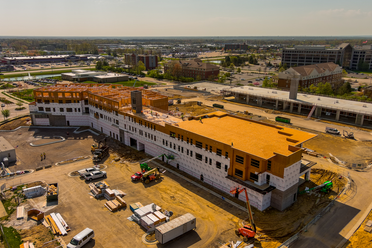 Construction site with a large building partially completed, surrounded by vehicles.