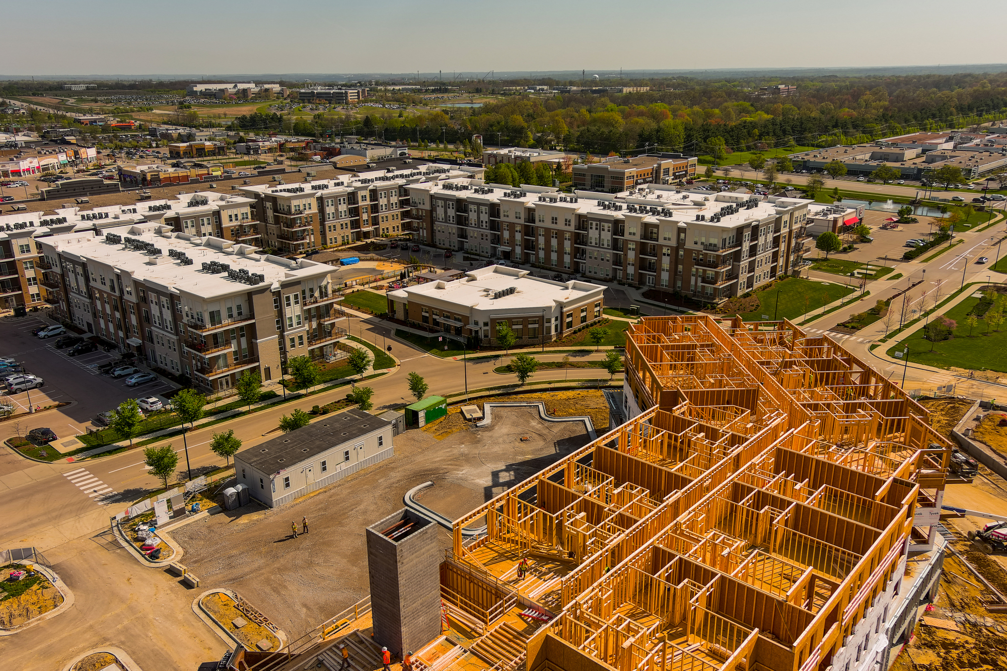 Aerial view of a construction site beside completed apartment buildings.