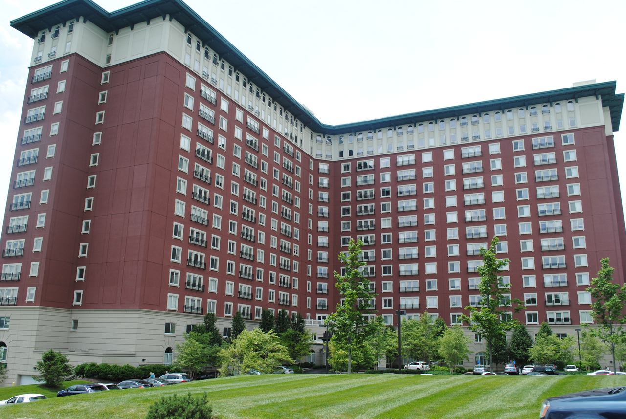 Red-brick high-rise building with green lawn and trees in the foreground.