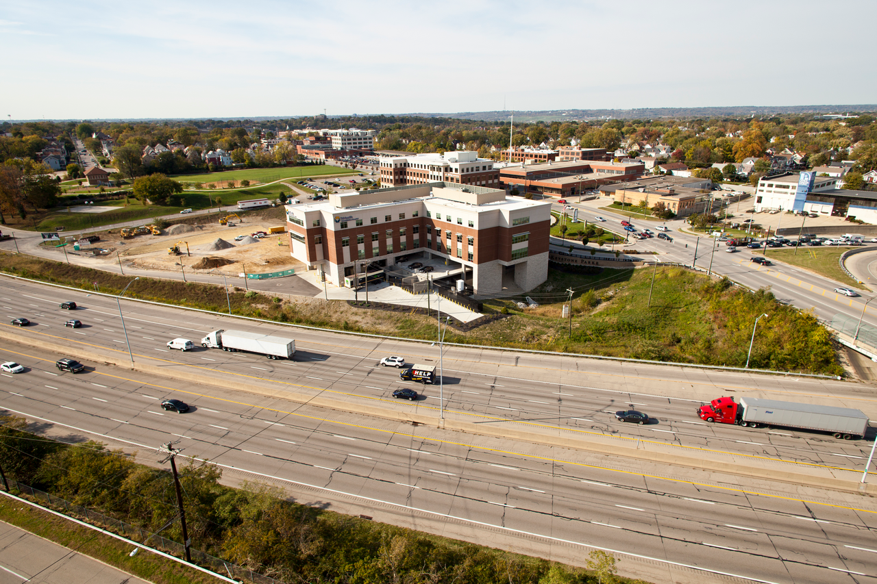 Aerial view of a highway with vehicles and a large building nearby.