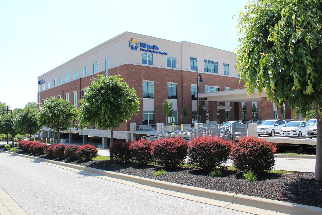 Hospital building with trees and parked cars.