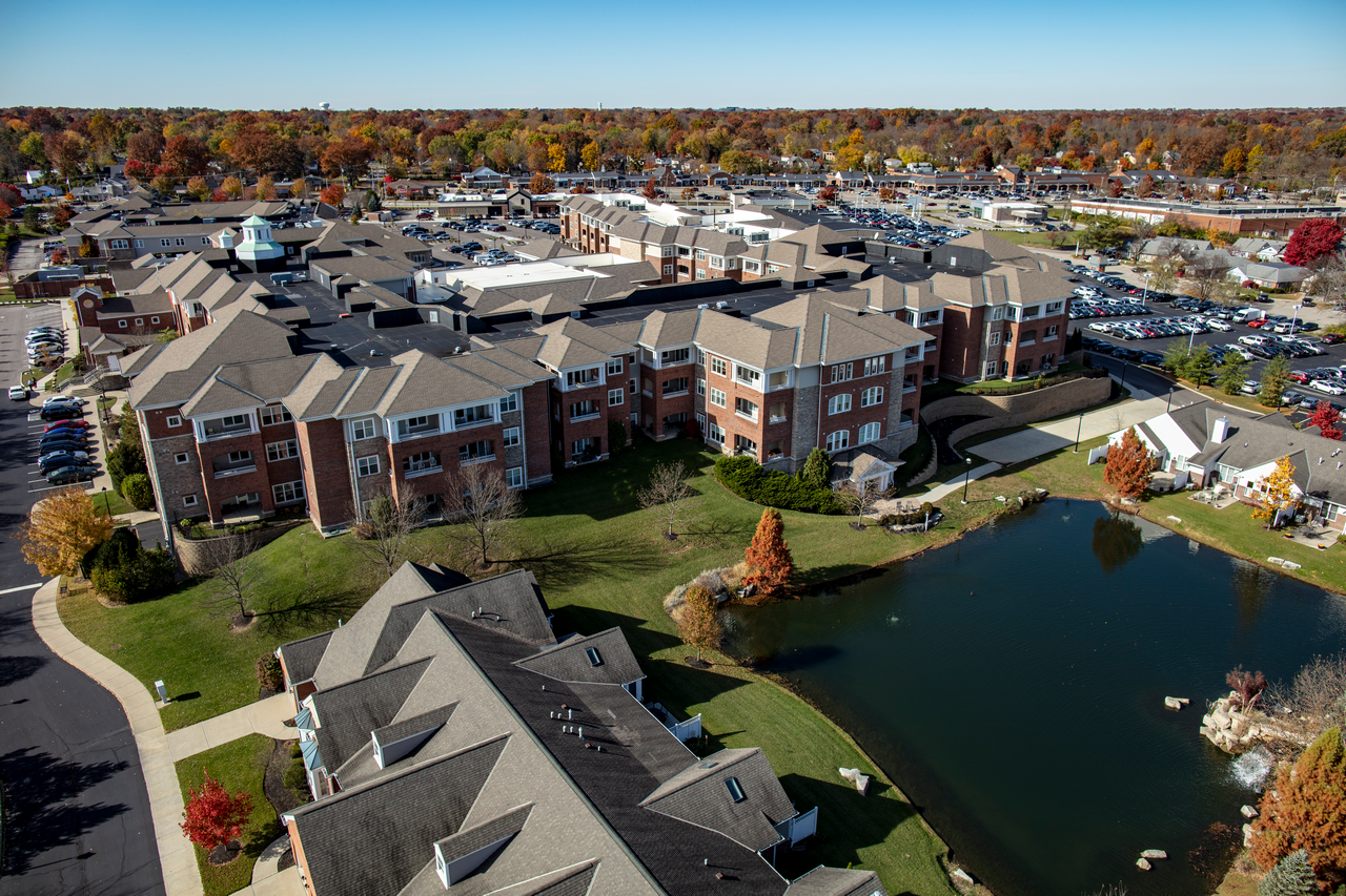 Aerial view of a large building complex with a pond in autumn.