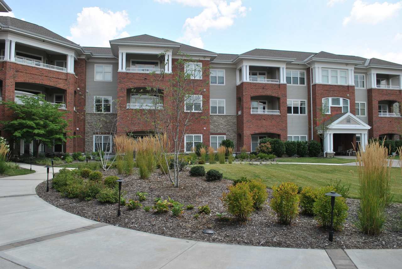 Three-story brick apartment building with landscaped garden.