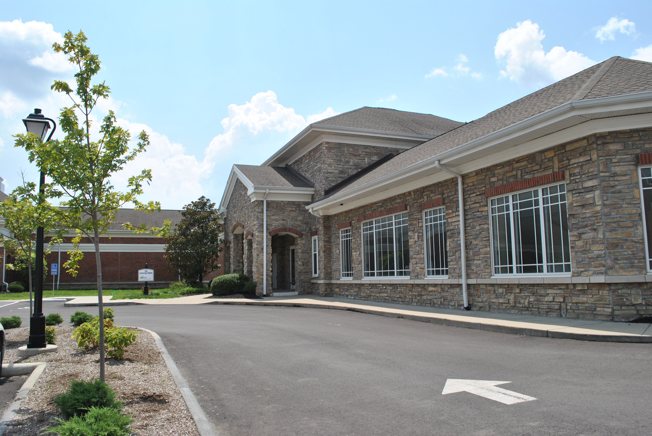 Modern stone building with large windows, blue sky above.
