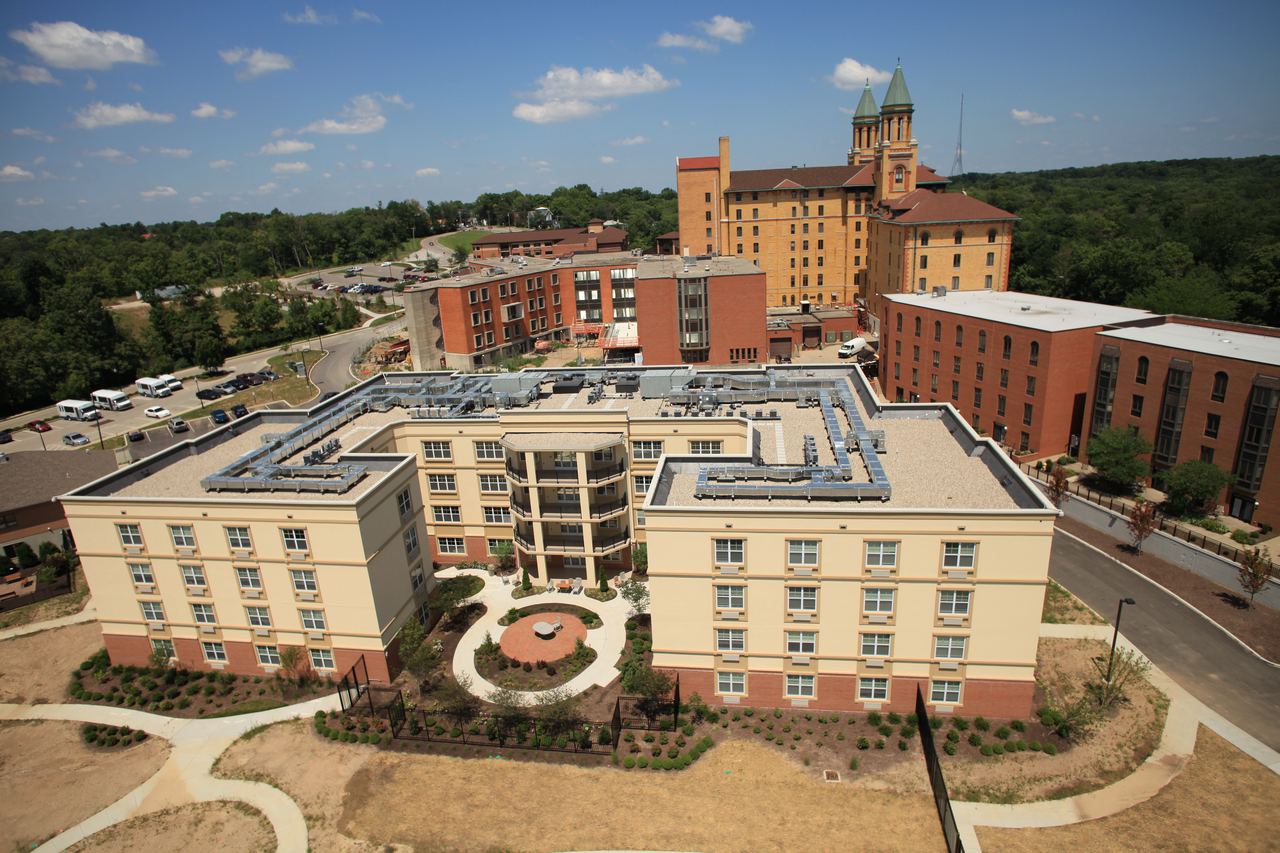 Campus buildings with a clock tower, greenery, and clear sky.