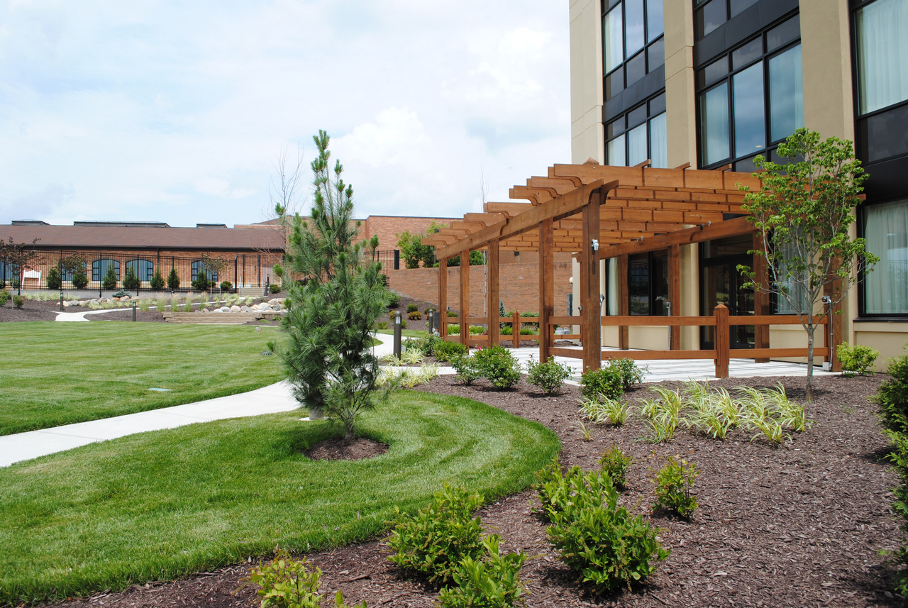Building with wooden pergola, landscaped gardens, and a curved pathway.