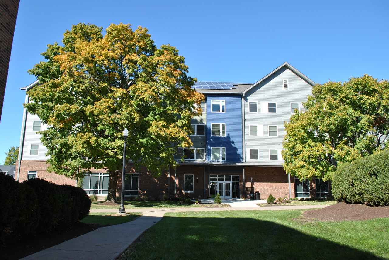 Four-story building with trees and a clear blue sky.