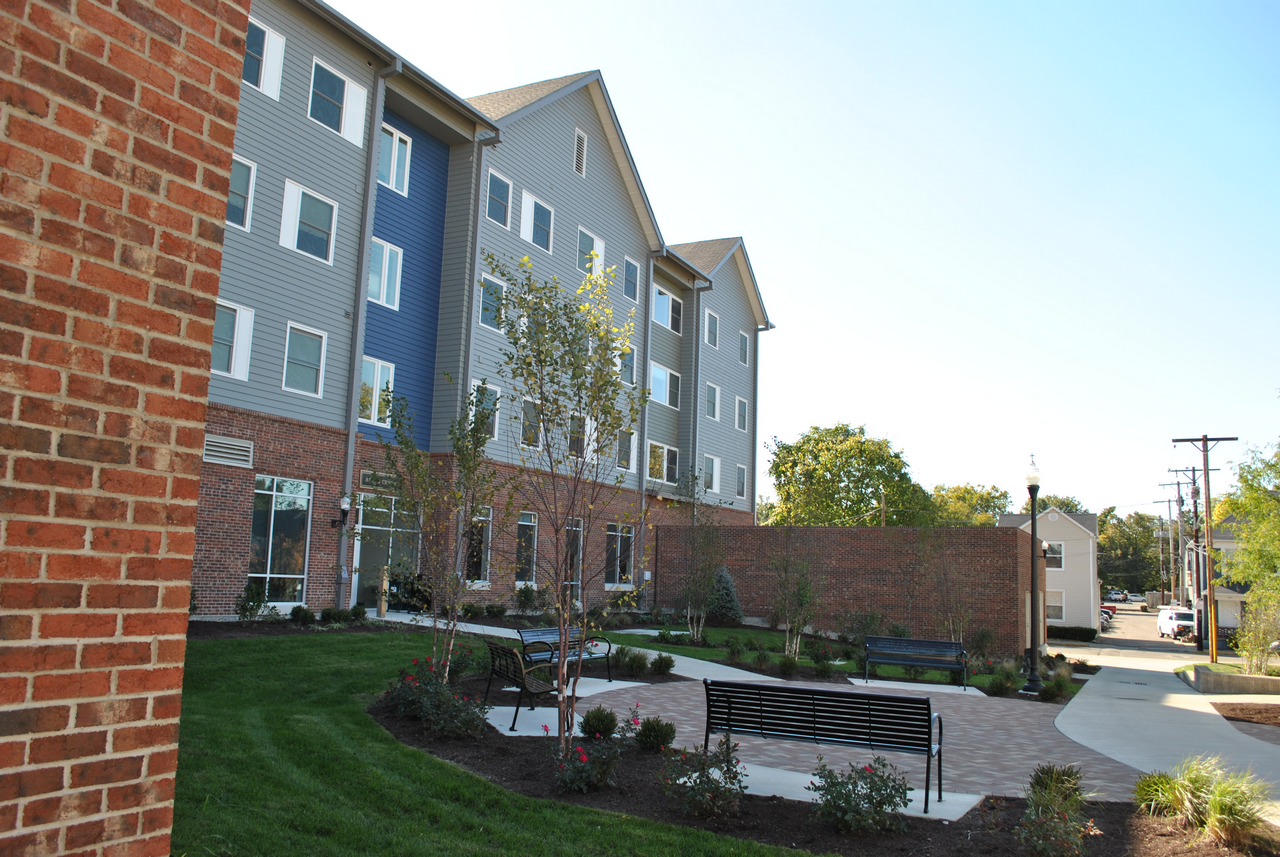 Brick building with landscaped garden and benches on a sunny day.