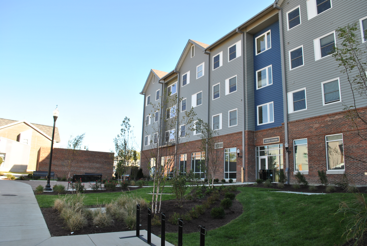 Four-story building with brick facade, surrounded by grass and a pathway.