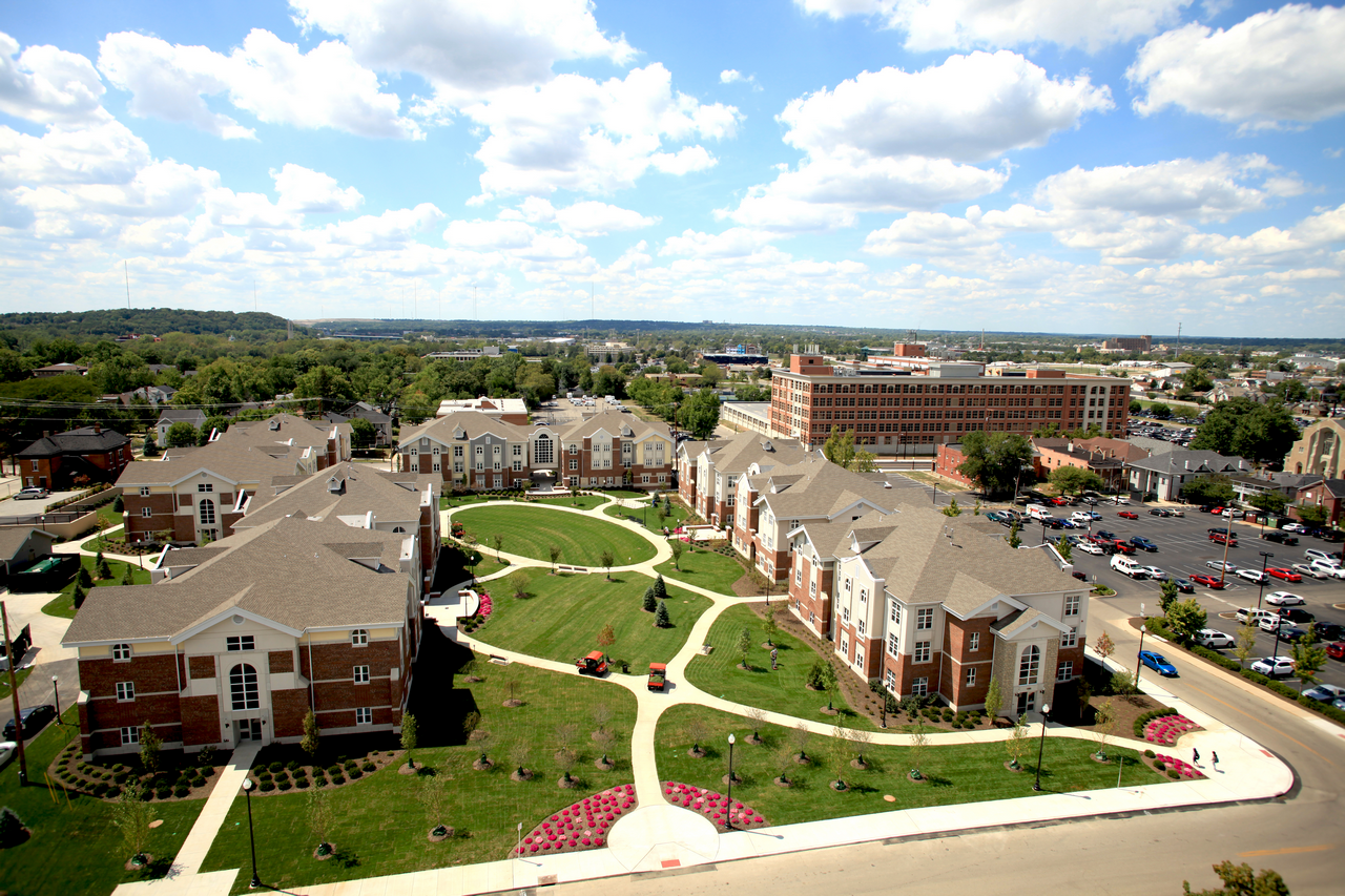 Aerial view of a landscaped college campus with brick buildings and pathways.