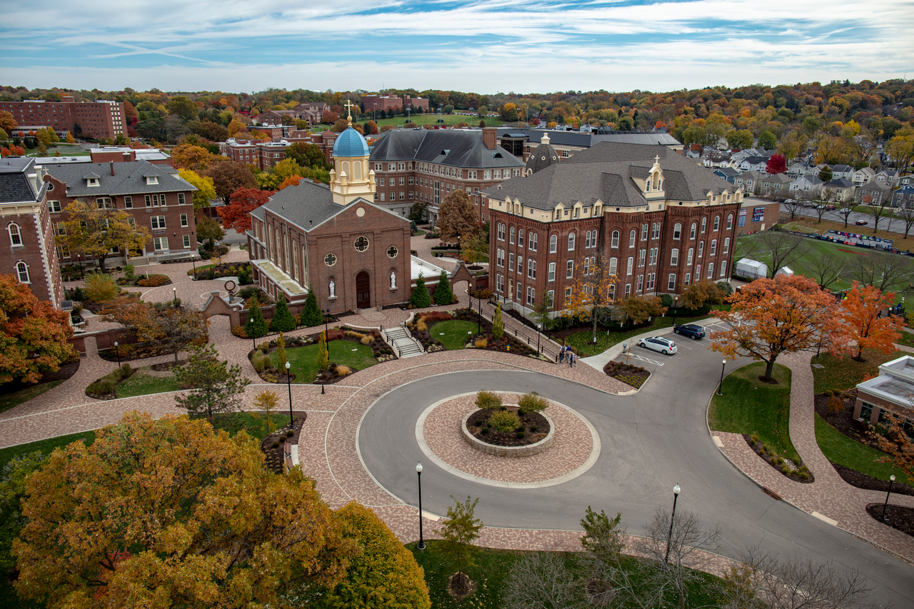 Campus buildings with autumn trees and a roundabout.