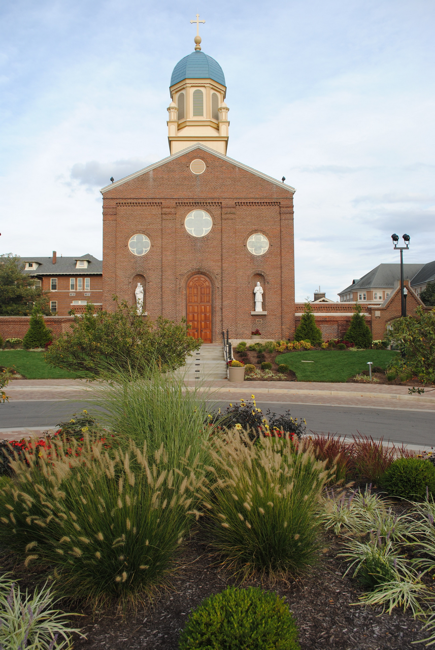 Red brick church with blue dome, surrounded by gardens and greenery.