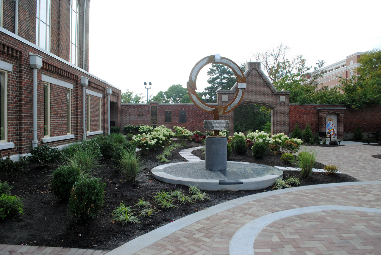 Courtyard with brick path, circular sculpture, and landscaped garden.