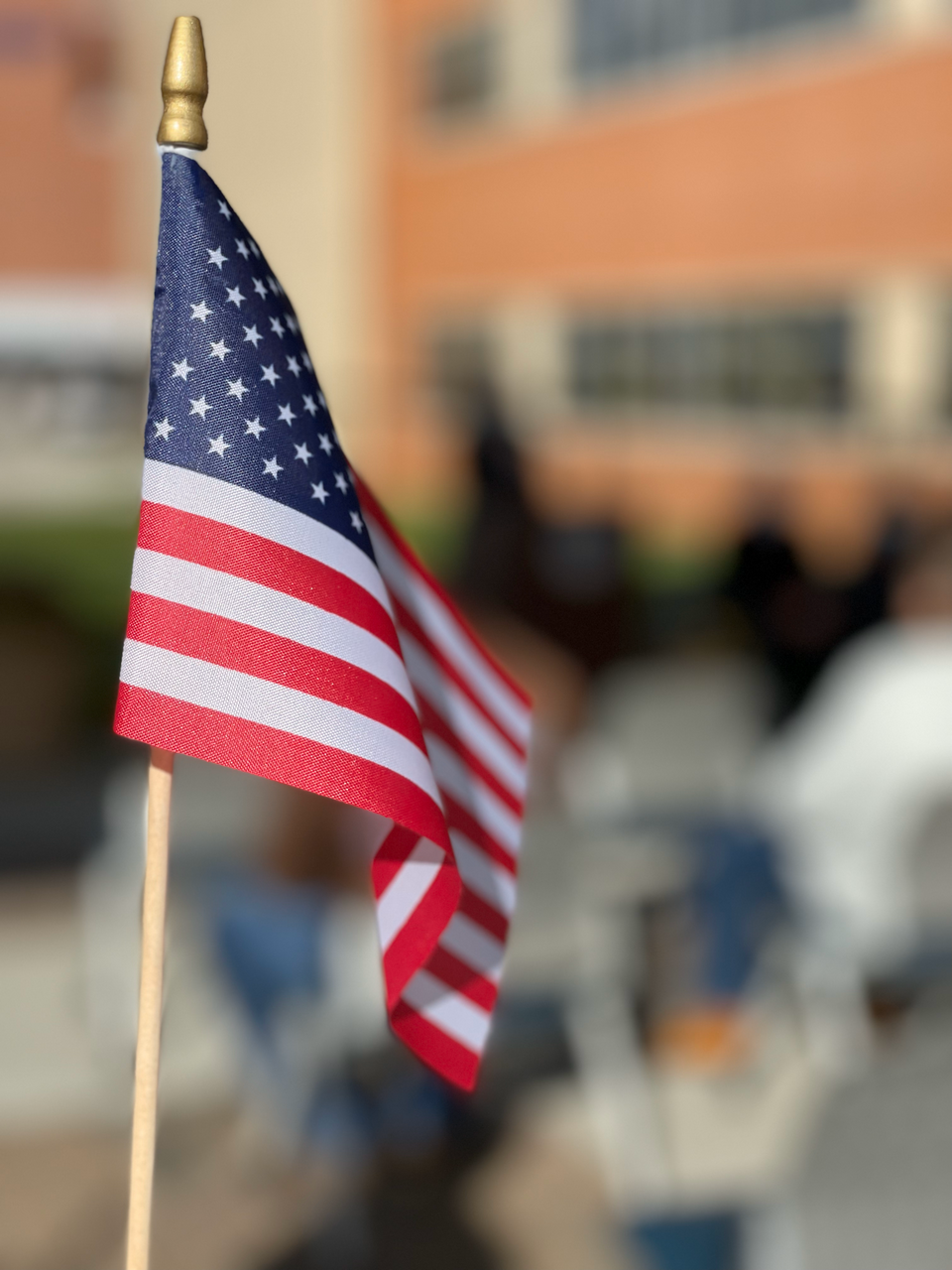 American flag on a small stick with blurred background.