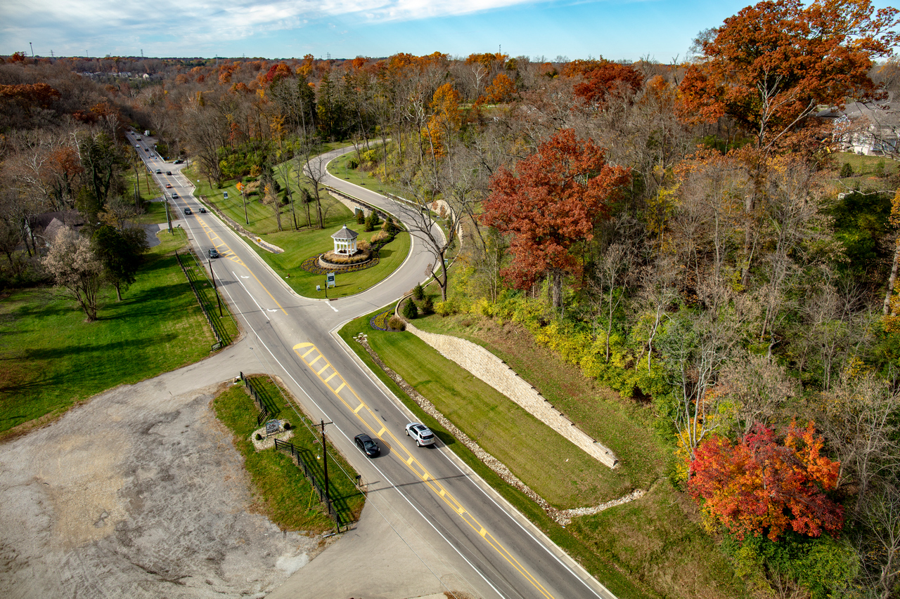 Aerial view of a winding road through autumn trees with colorful foliage.