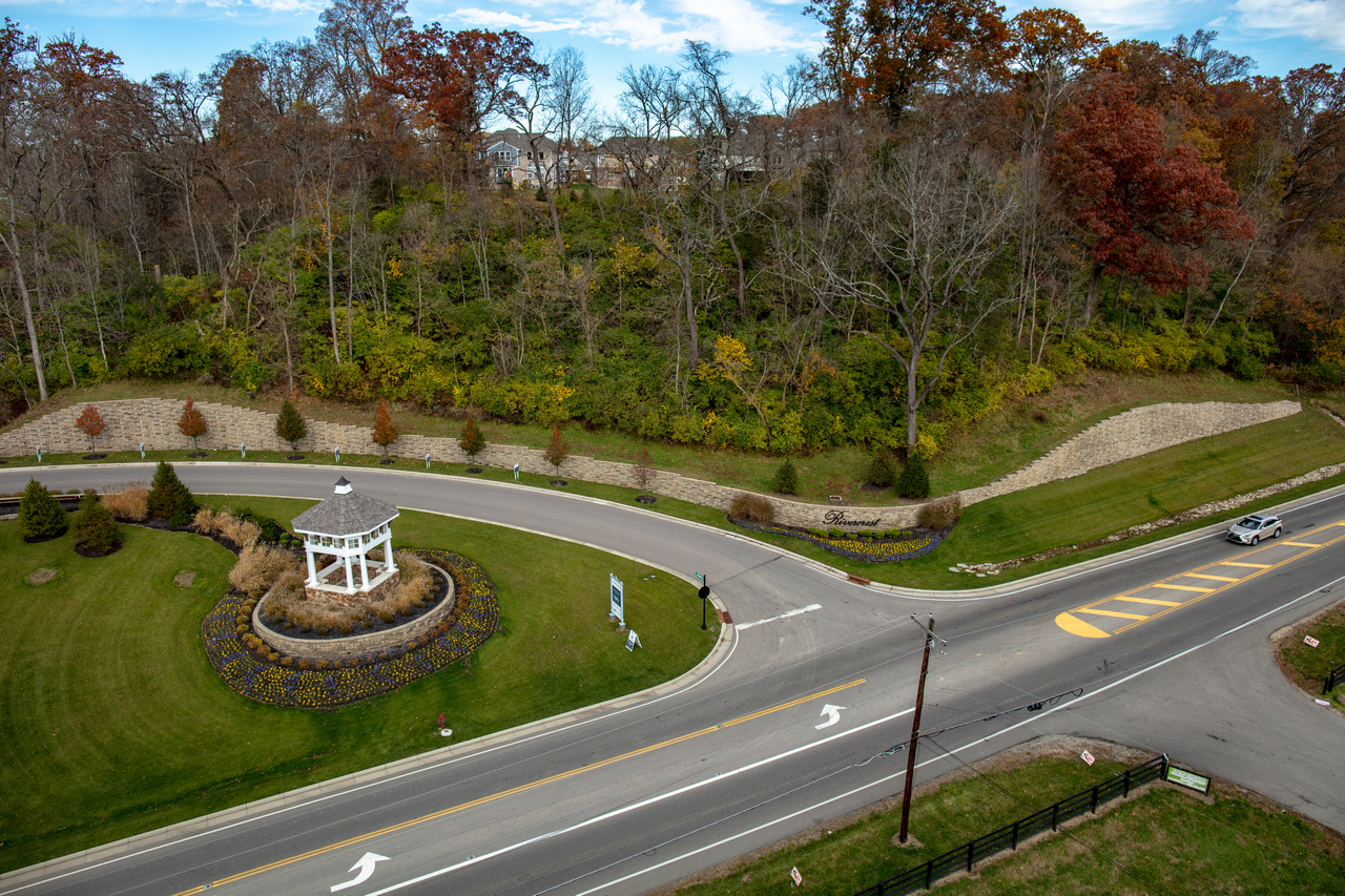 Aerial view of a road roundabout with a white gazebo and autumn trees.