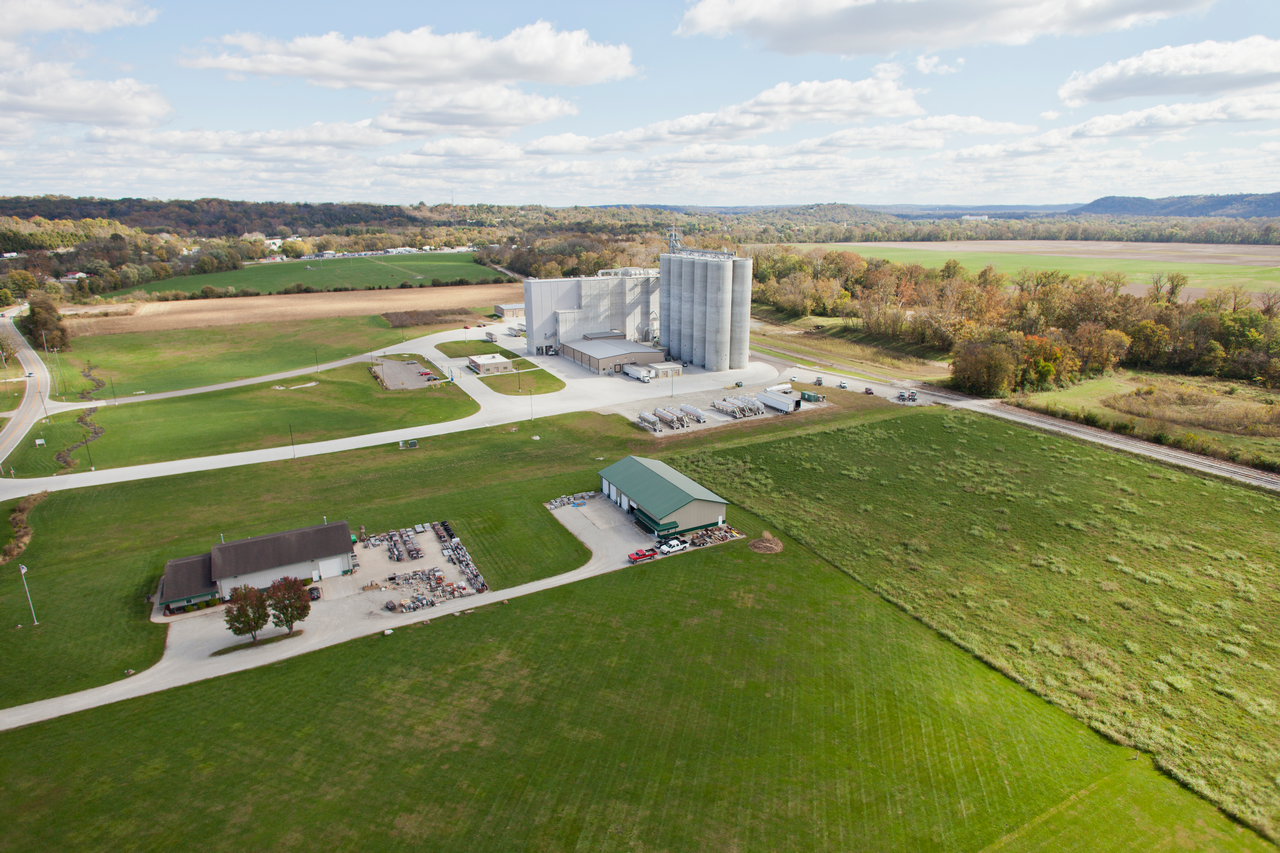 Aerial view of a rural farm with silos and green fields.