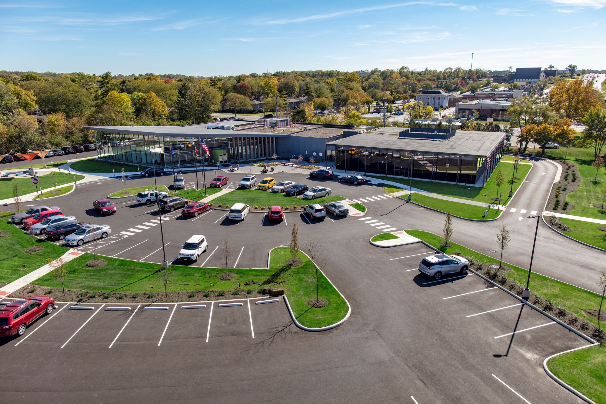 Aerial view of parking lot and modern building with surrounding trees.