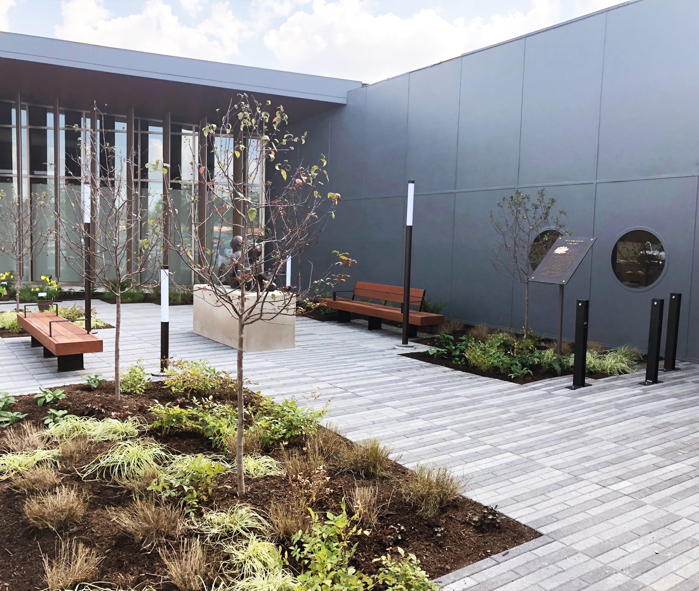 Rooftop garden with benches, plants, and a gray wall background.