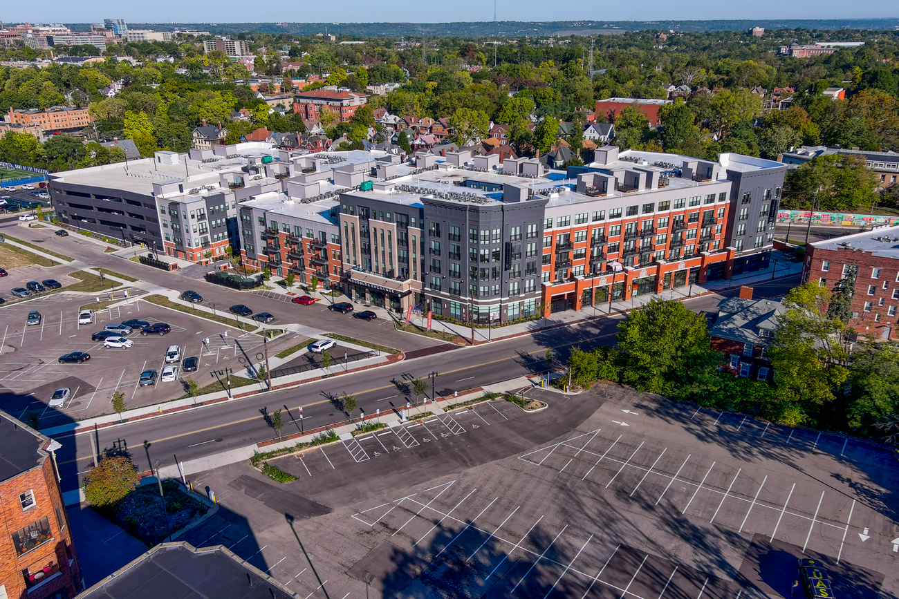 Aerial view of a modern building complex with parking lot and trees.