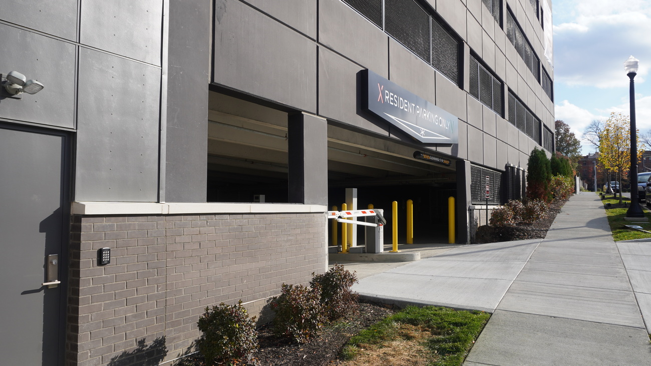 Parking garage entrance beside a sidewalk on a sunny day.