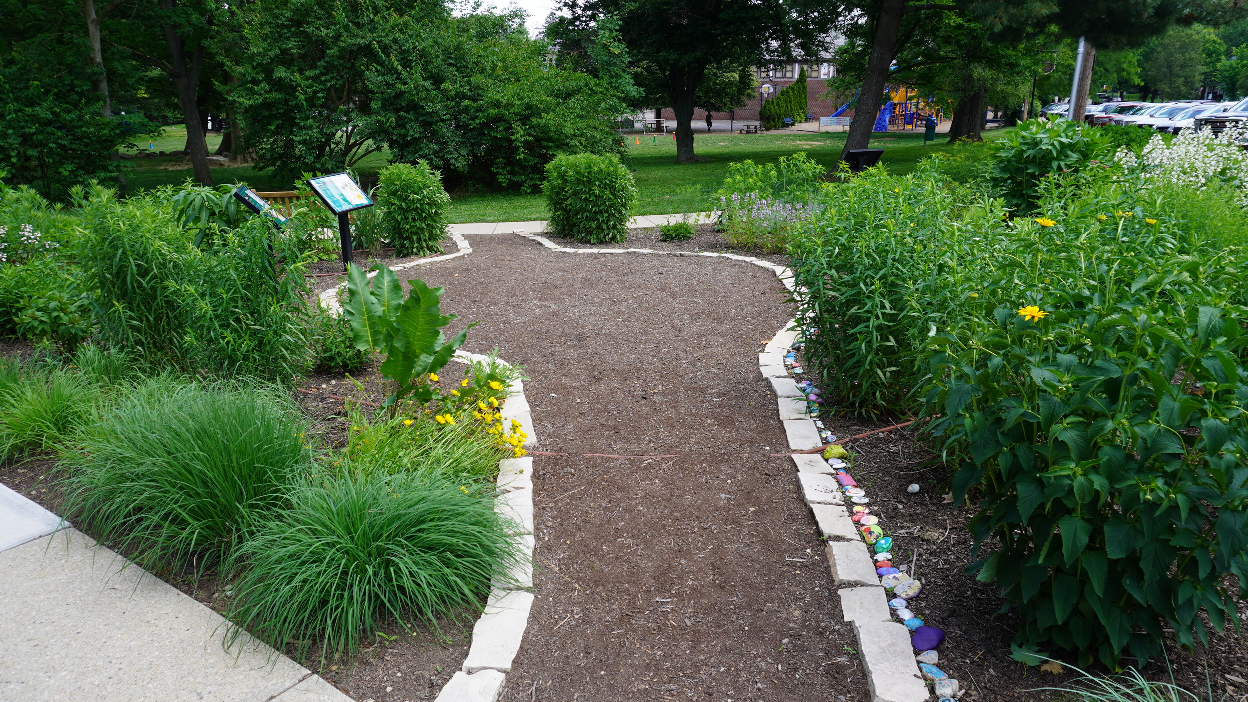Curved garden path with lush greenery and colorful flowers.