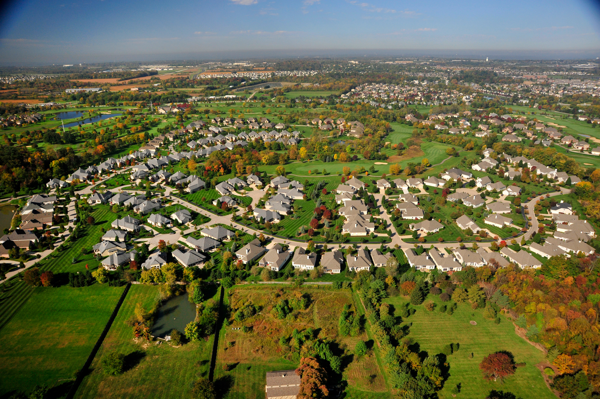 Aerial view of a suburban neighborhood with green lawns and scattered trees.