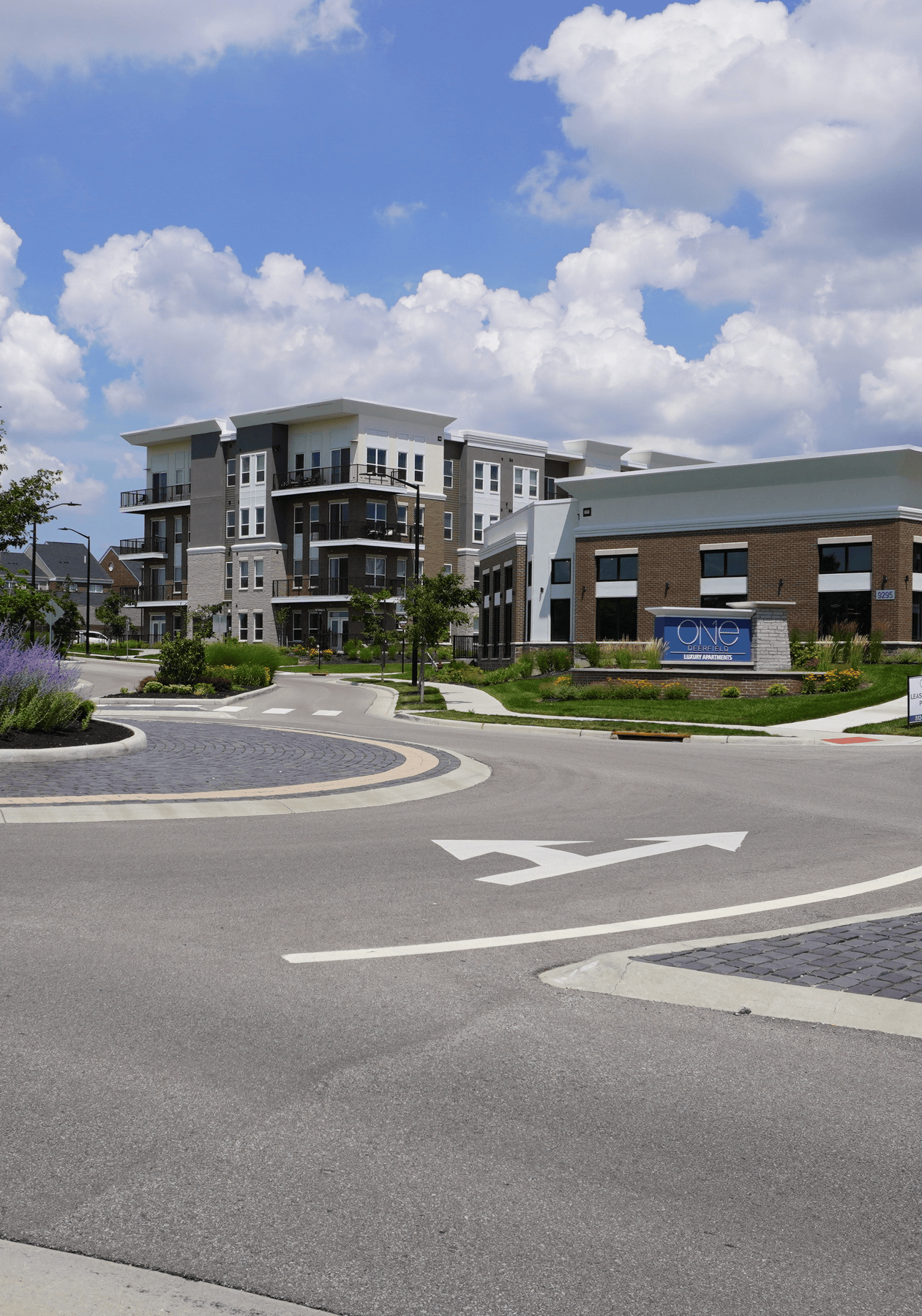 The District at Deerfield - Deerfield Twp, OH Modern apartment complex under a blue sky with fluffy clouds.