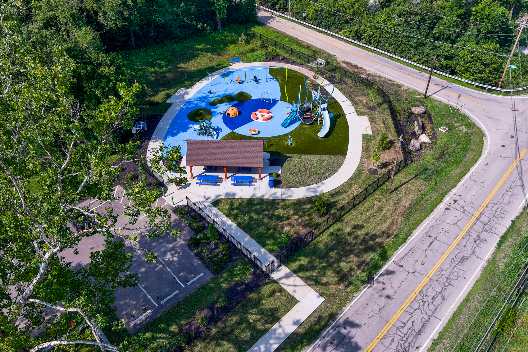 Aerial view of a playground with splash pad and surrounding greenery.
