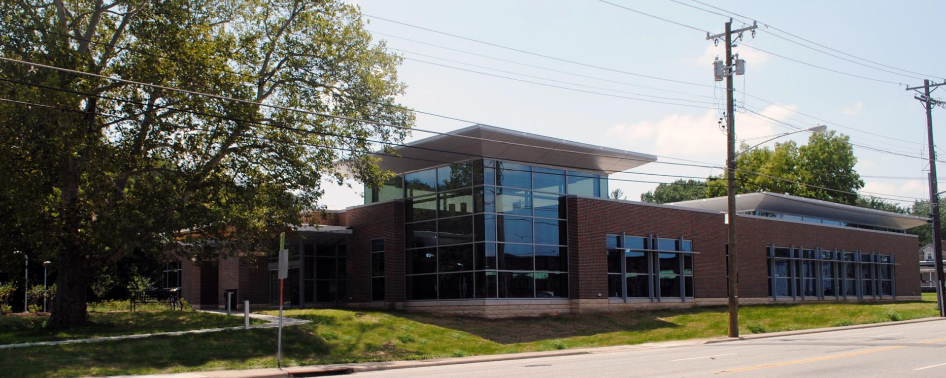 brick library building with big windows and a tree out front