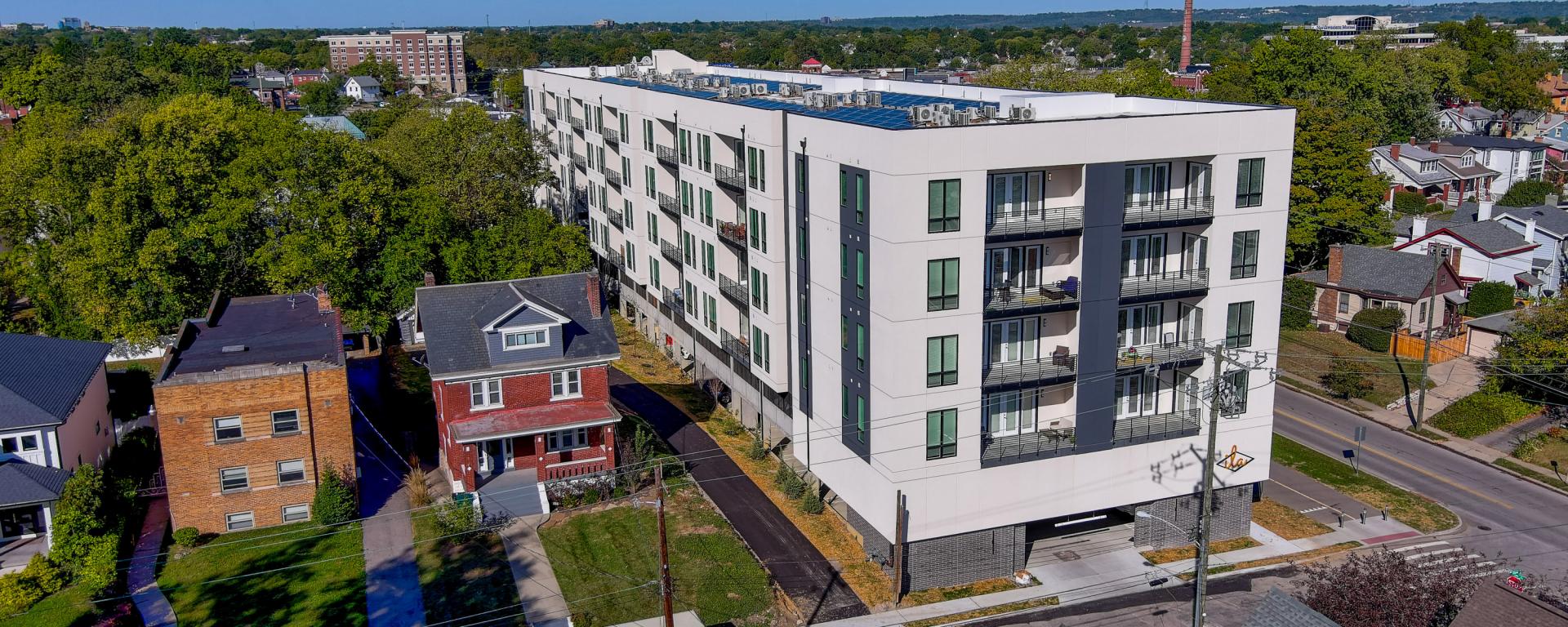 aerial photo of white apartment building with small red house next to it